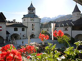 Hohenwerfen Fortress - view through red flowers to the castle courtyard