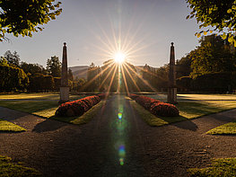 Hellbrunn Palace & Trick Fountains - View through an avenue of trees in the castle park to the shining sun