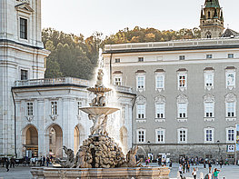 Brunnen am Residenzplatz mit Besuchern und Salzburger Residenz im Hintergrund